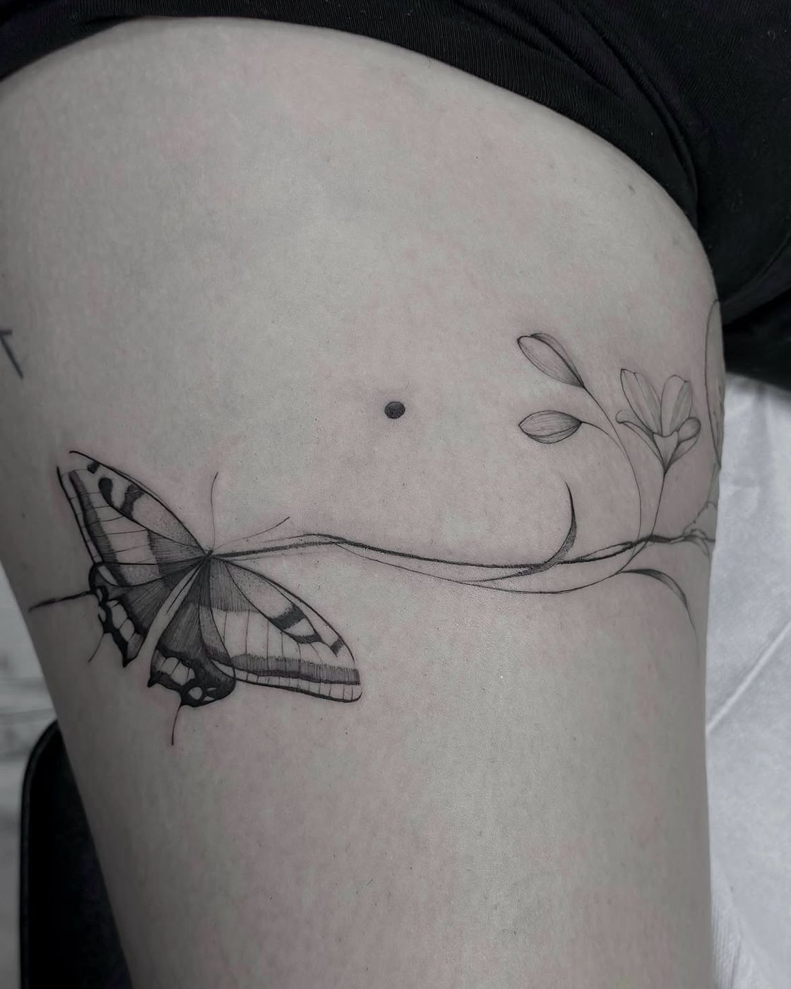 Schmetterling mit Ranke um den Oberschenkel